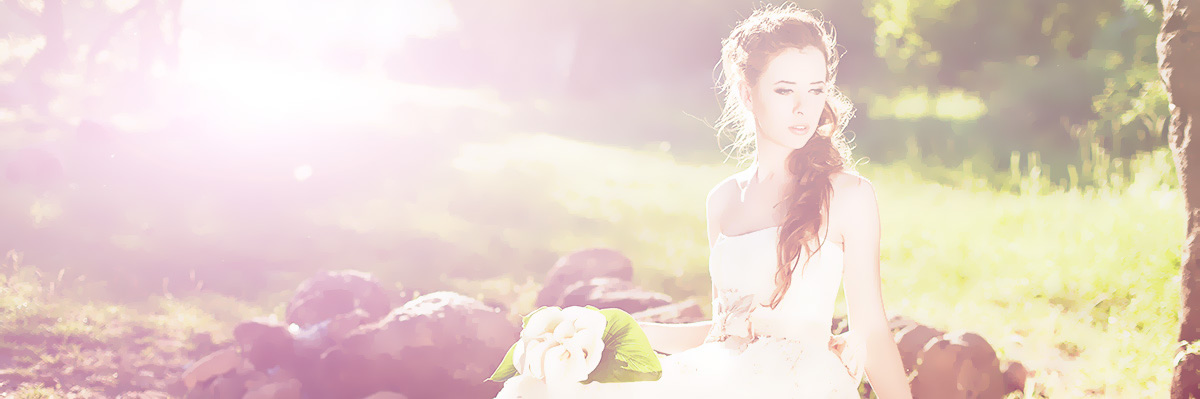 A bride holding white roses in a sunny meadow
